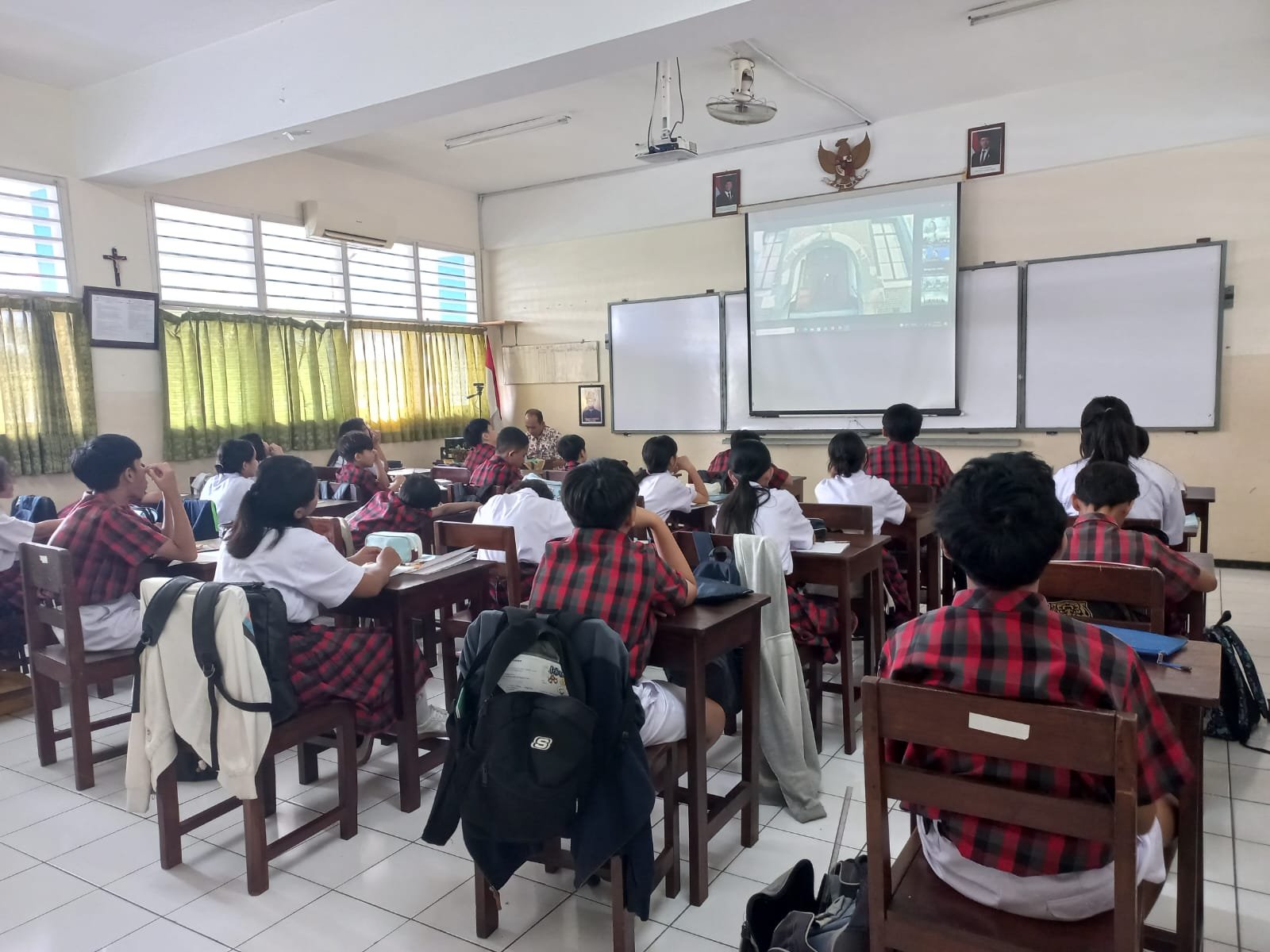 Siswa dan Siswi bersama dengan Guru sedang melaksanakan doa Novena Yubile 75 Tahun Yayasan Tarakanita di ruang kelas masing - masing