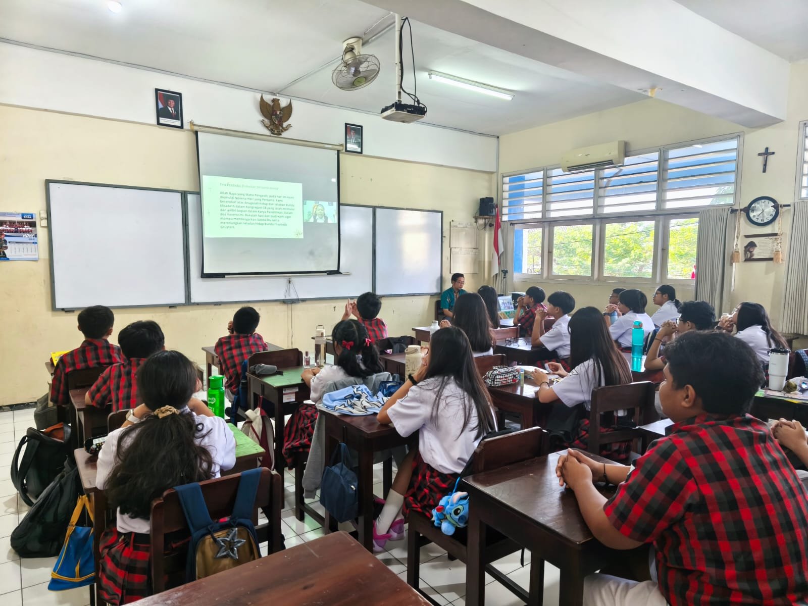 Siswa dan Siswi bersama dengan Guru sedang melaksanakan doa Novena Yubile 75 Tahun Yayasan Tarakanita di ruang kelas masing - masing