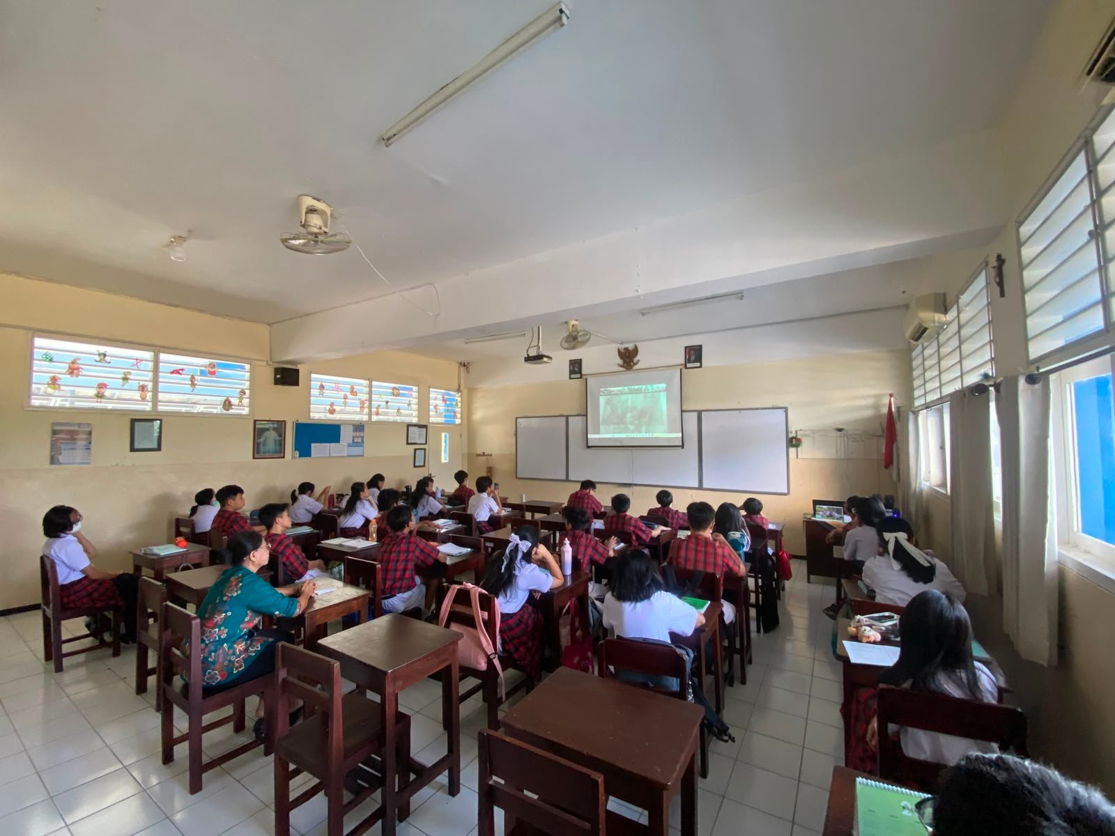 Siswa dan Siswi bersama dengan Guru sedang melaksanakan doa Novena Yubile 75 Tahun Yayasan Tarakanita di ruang kelas masing - masing