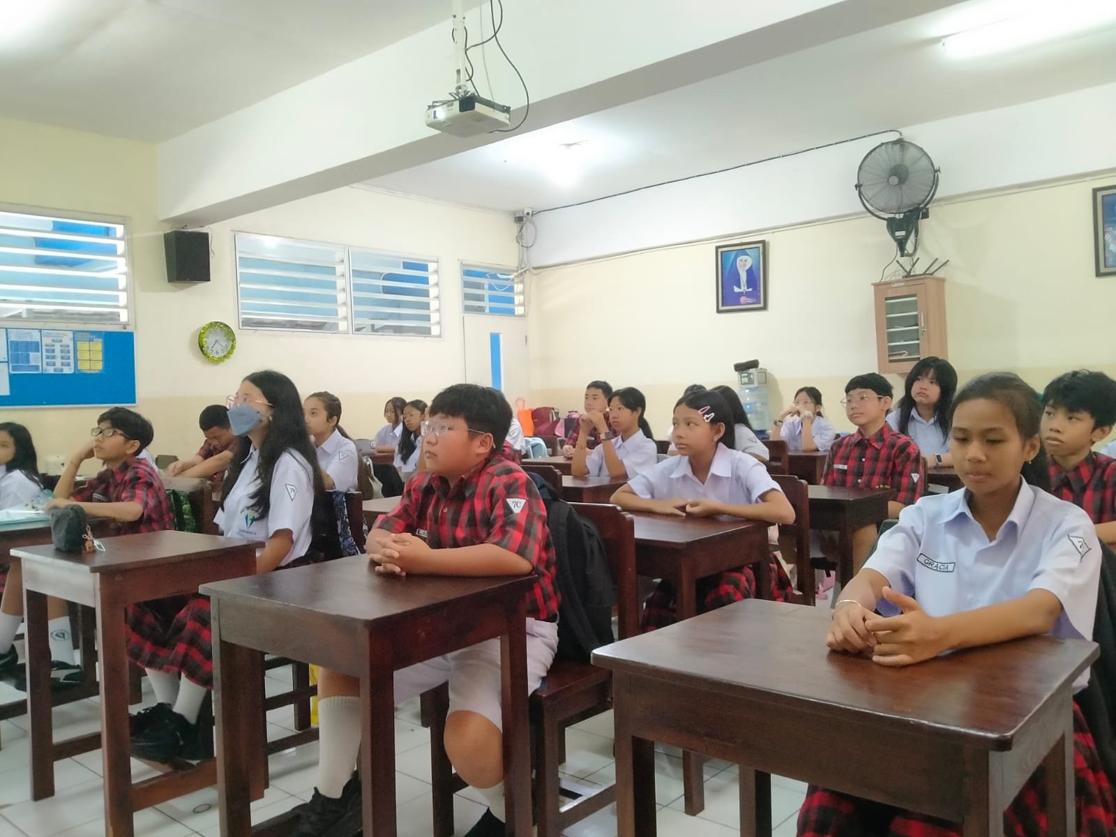 Siswa dan Siswi bersama dengan Guru sedang melaksanakan doa Novena Yubile 75 Tahun Yayasan Tarakanita di ruang kelas masing - masing